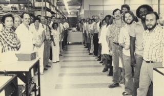 一群贝克曼仪器公司的科学家站在实验室里，对着镜头微笑