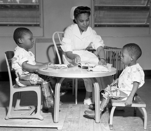 护士坐在小表 带两个孩子的腿支架